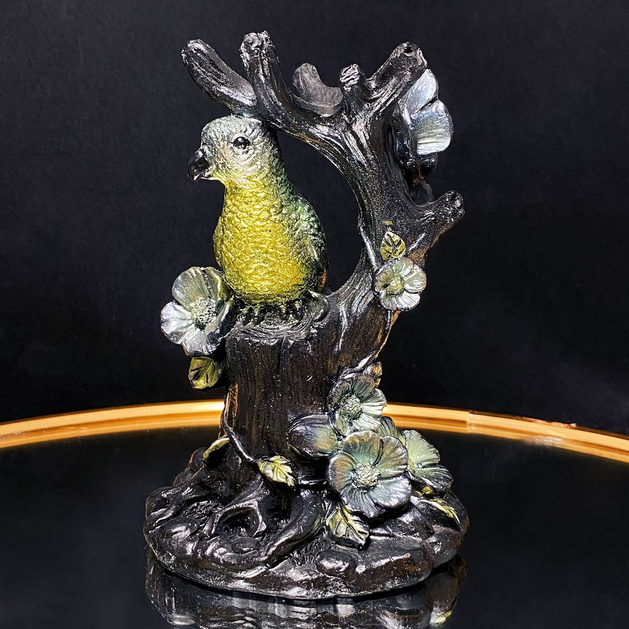 Resin parrot on the tree sphere stand